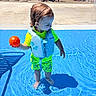 toddler, child, pool, water, life_jacket, orange_ball, swimwear, sunny_day, shadow, outdoor, people, lounge_chairs, swimming_pool, summer, recreation, play, fun, water_play, vacation, park