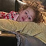 child, toddler, curly_hair, couch, pillow, blanket, indoor, relaxed, clothing, patterned, soft, resting, home, cozy, young_child, portrait, person, furniture, casual, comfort