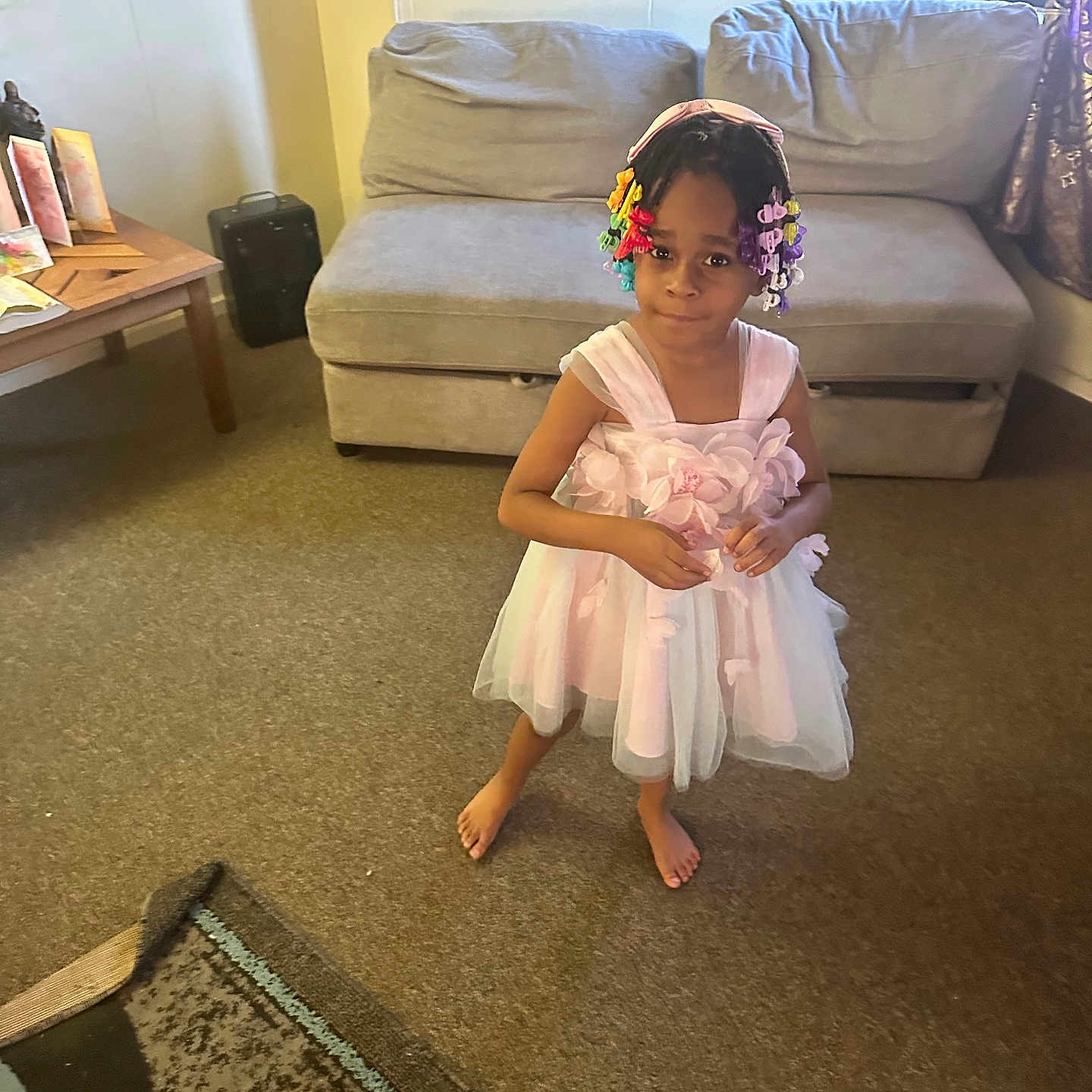 Kylie joined the competition — help win amazing prizes! child, girl, dress, pink, barefoot, carpet, living_room, sofa, couch, table, hair_beads, colorful, portrait, indoor, curious, smile, furniture, wall_art, floor, home