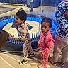 child, children, indoor, museum, exhibit, glass, curious, blue_lighting, floor, casual_clothing, sneakers, hoodie, pink_outfit, grey_outfit, standing, exploration, reflection, young, person, group