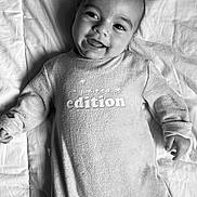 Lucas a rejoint le concours — aidez-le/la à gagner de superbes lots ! baby, infant, smiling, onesie, blanket, black_and_white, portrait, happy, lying_down, cute, face, child, clothing, text_on_clothing, soft_texture, cozy, indoors, young_child, expression, sleepwear