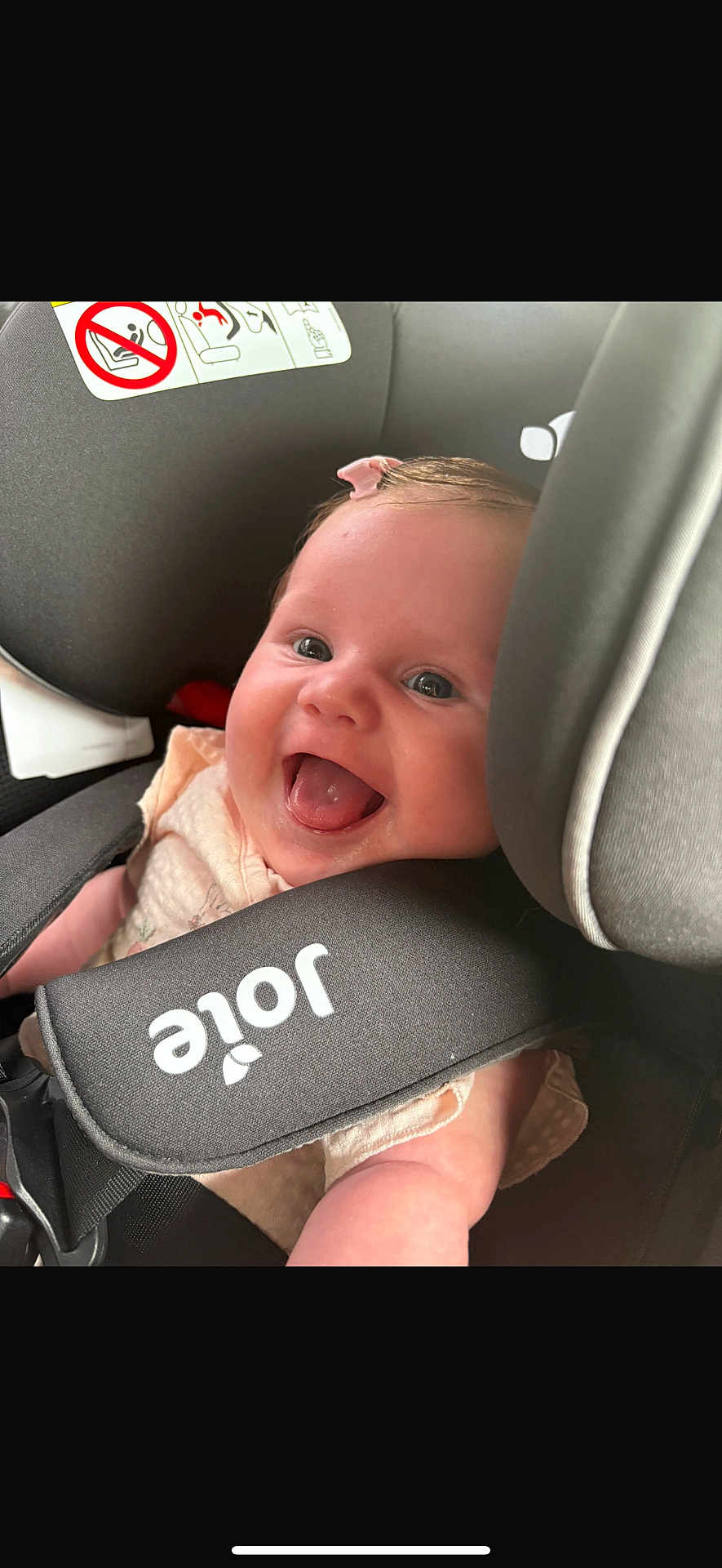 Gracie is registered to the contest to win money with this photo: baby, child, car_seat, smile, happy, infant, seat_belt, pink_bow, closeup, cute, person, safety, car_interior, joy, portrait, child_safety, infant_clothing, strapped, seat, head_support