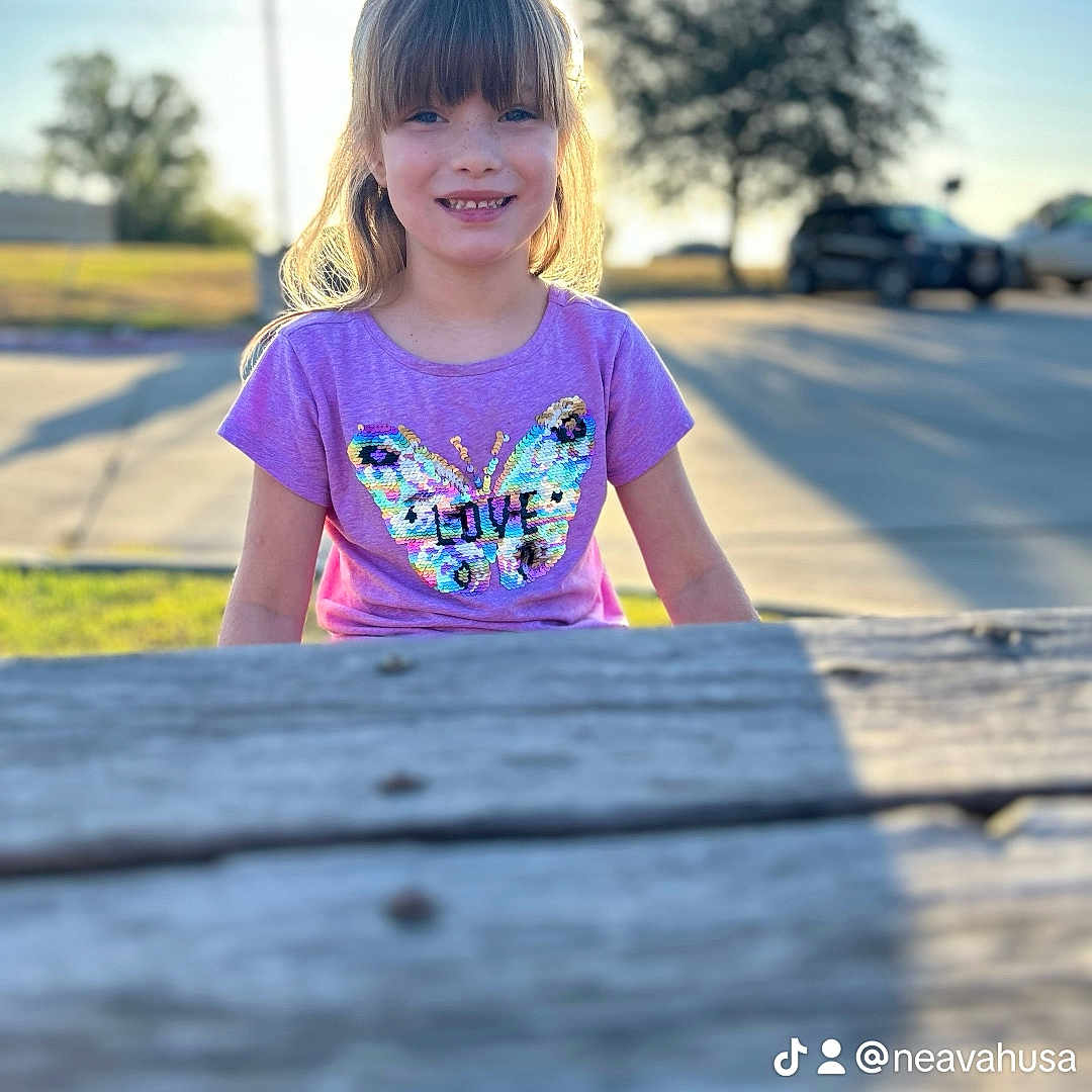 Skylar is registered to the contest to win money with this photo: boardwalk, bridge, child, clothing, face, female, girl, grass, head, outdoors, path, person, photography, plant, portrait, t_shirt, tree, water, waterfront, wood