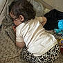 toddler, child, sleeping, curly_hair, white_shirt, leopard_print, pants, blanket, playpen, toy, blue_toy, cozy, nap, indoor, baby, infant, soft, peaceful, clothing, rest