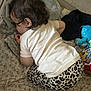 toddler, child, sleeping, curly_hair, white_shirt, leopard_print, pants, blanket, bedspread, toy, blue_toy, patterned_bedspread, indoor, cozy, infant, resting, soft_fabric, cute, young_child, naptime