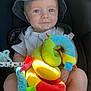 baby, child, denim_hat, bucket_hat, car_seat, plush_toy, colorful_toy, soft_toy, straps, blue_eyes, cute, infant, smiling, indoor, seatbelt, child_safety, toy_snake, happy, person, closeup