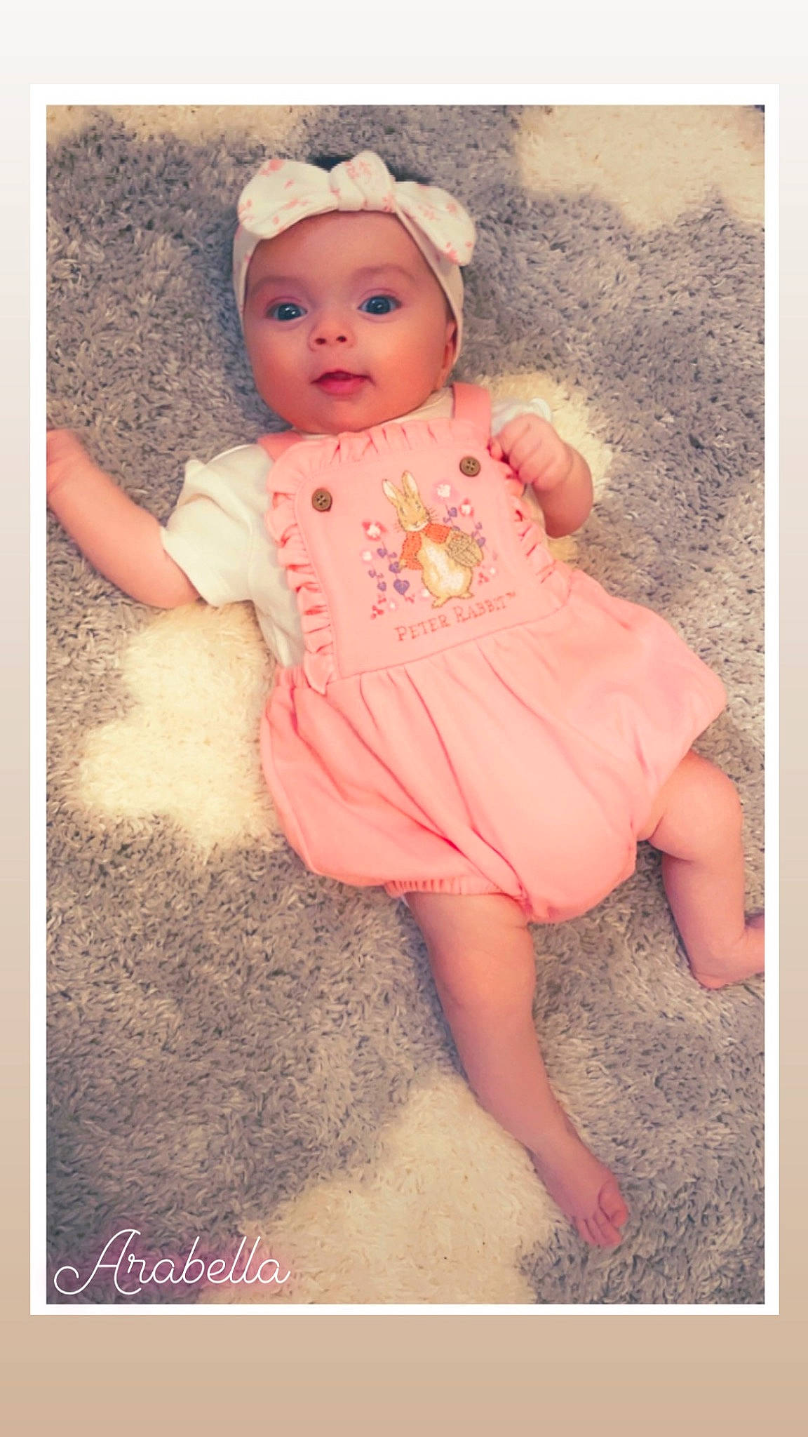 Arabella is registered to the contest to win money with this photo: baby, baby_products, baby_toddler_clothing, cap, cheek, child, fashion_accessory, happy, headwear, magenta, pattern, peach, person, photograph, pink, portrait_photography, sitting, skin, sleeve, stock_photography