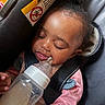 Malasianay is registered to the contest to win money with this photo: baby, infant, child, sleeping, bottle, feeding, car_seat, seatbelt, passenger, portrait, closeup, face, eyes_closed, hair, pink_clothing, indoors, vehicle, safety_label, hands, peaceful
