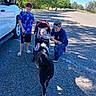Rebekah is registered to the contest to win money with this photo: child, baby, man, dog, fish, stroller, vehicle, road, trees, gravel, sunlight, shadow, outdoor, casual_clothing, cap, leash, interaction, parked_car, curious, family