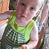 Rebekah is registered to the contest to win money with this photo: adult_leg, blue_eyes, cabinet, casual, child, curious_expression, floor, food, footwear, green_clothing, home, indoor, natural_light, person, portrait, short_hair, standing, striped_dress, toddler, wooden_furniture