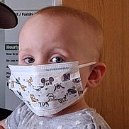 Rebekah is registered to the contest to win money with this photo: baby, child, curious, cute, expression, eyes, face_mask, grey_shirt, head, health, heart_pattern, indoor, mask, mickey_mouse, person, pink_bow, portrait, protection, toddler, young_child