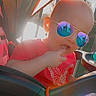 baby, baby_accessory, casual, child, cute, daylight, finger, hand, outdoor, playful, portrait, railing, red_shirt, reflection, seat, stroller, sunglasses, sunlight, toddler, toy