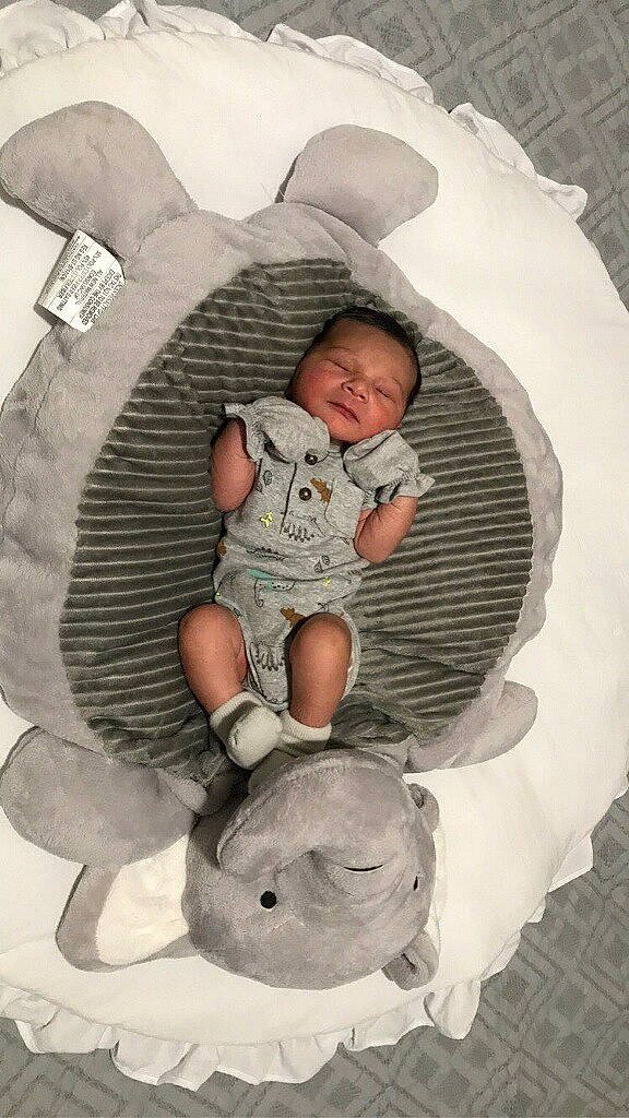 Micheal is registered to the contest to win money with this photo: baby, baby_products, baby_sleeping, baby_toddler_clothing, bed, bedding, bedtime, black, child, comfort, human_body, linens, mammal, organ, person, pillow, room, sitting, textile, toddler