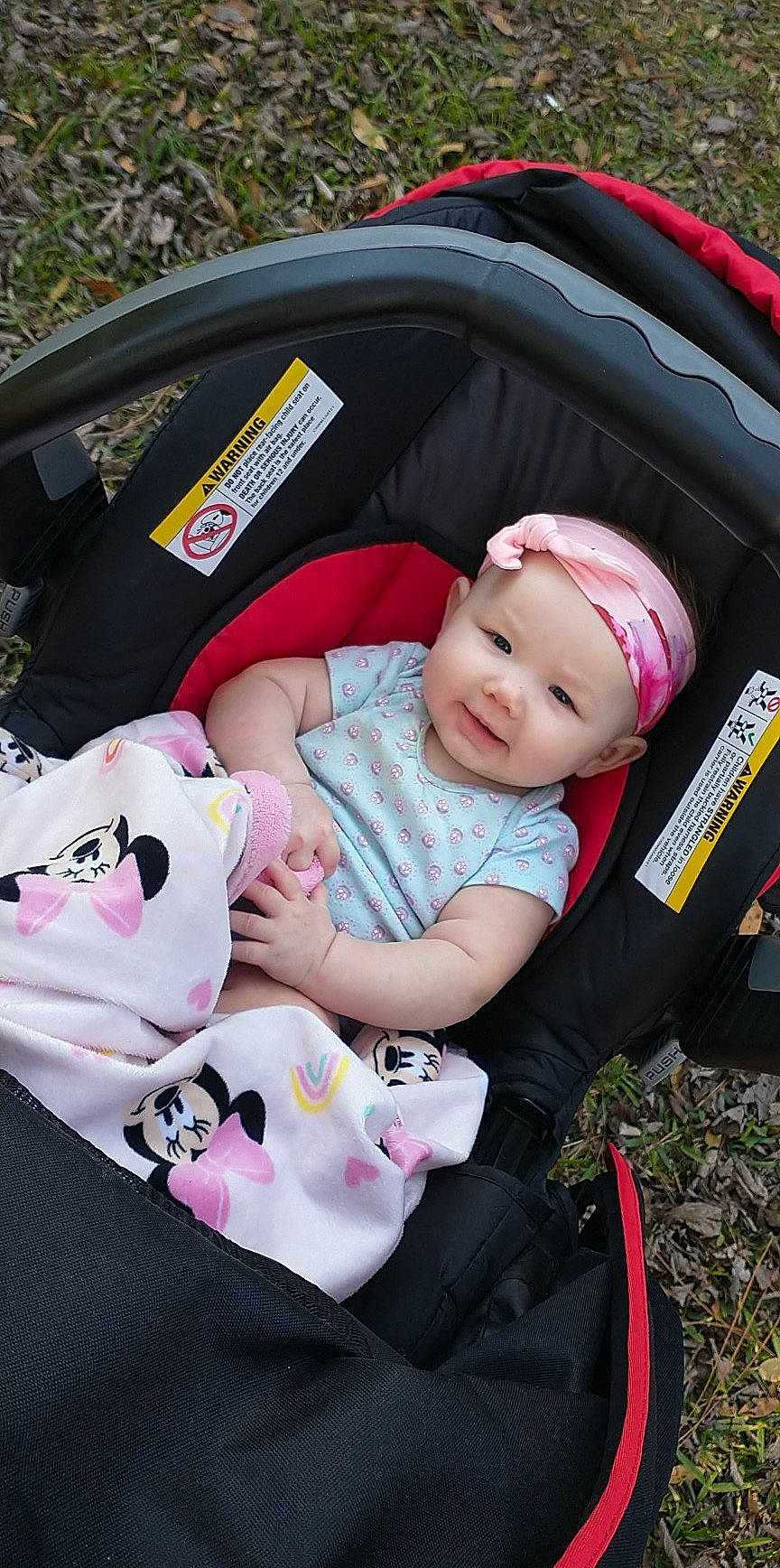 Scarlett is registered to the contest to win money with this photo: auto_part, baby, baby_carriage, baby_products, baby_toddler_clothing, beauty, car_seat, child, comfort, family_car, grass, head, headwear, mammal, motor_vehicle, person, pink, product, sitting, smile