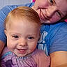 adult, baby, blue_shirt, casual, child, closeup, clothing, cute, face, family, hair, happy, indoor, person, portrait, purple_outfit, skin, smile, tattoo, toddler