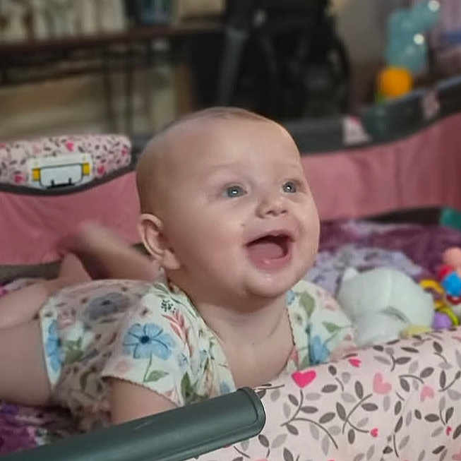 Holly is registered to the contest to win money with this photo: baby, infant, playpen, smiling, happy, tummy_time, toys, colorful, blanket, child, indoor, cute, young, person, pattern, fabric, soft, play, joyful, expression