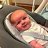 Alfie is registered to the contest to win money with this photo: baby, infant, smile, face, child, seat, cushion, straps, white_clothing, indoor, furniture, head, skin, eyes, cheerful, happy, closeup, portrait, newborn, baby_seat