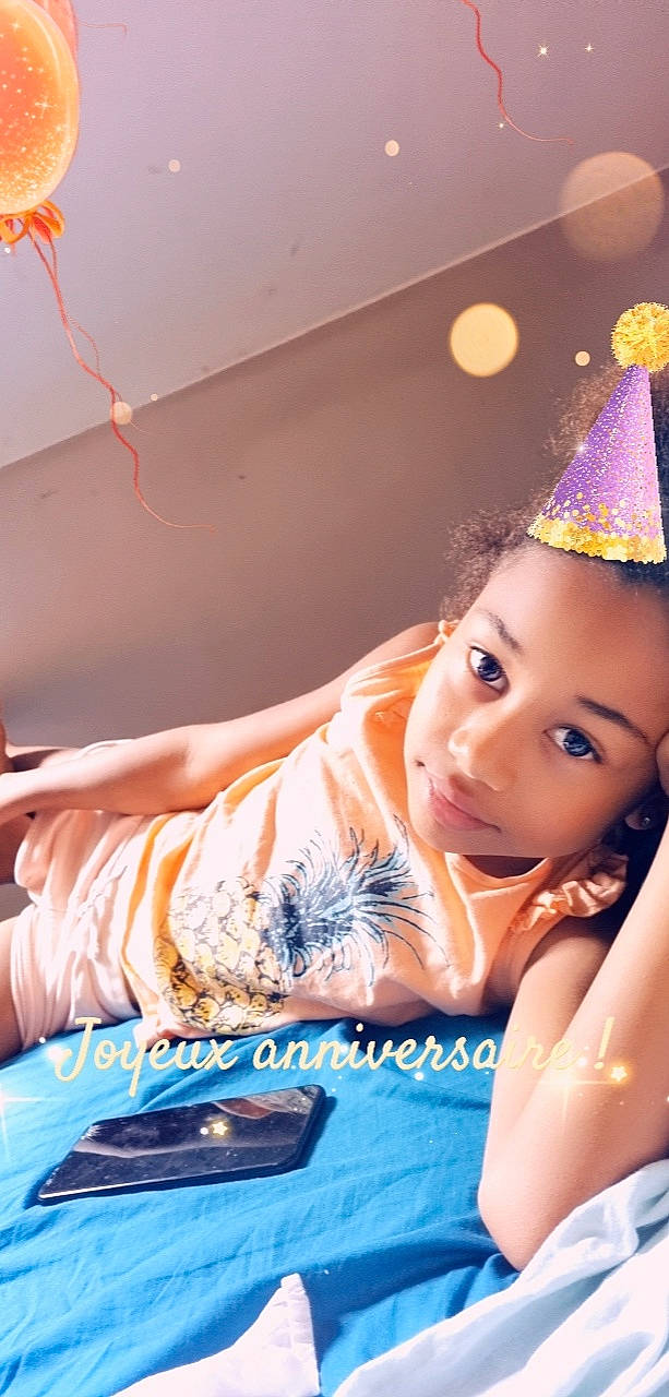 Aliyah a rejoint le concours — aidez-le/la à gagner de superbes lots ! birthday, child, cone, costume_hat, electric_blue, event, fashion_accessory, flash_photography, fun, happy, headgear, headpiece, leisure, party, party_hat, party_supply, person, portrait_photography, room, sitting