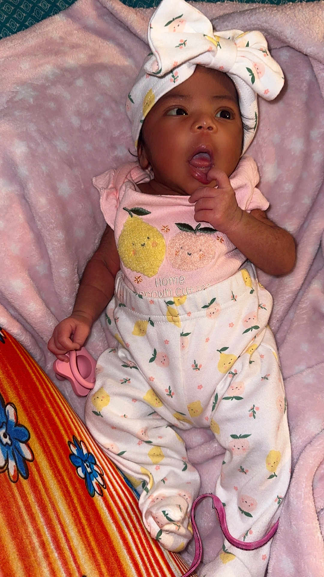 Ellie is registered to the contest to win money with this photo: baby, infant, child, pajamas, headband, bow, pink, blanket, pacifier, clothing, cute, face, hand, footie_pajamas, pattern, fruit, yellow, orange, soft, indoors