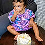 toddler, child, cake, frosting, messy, curly_hair, purple_clothing, bunny_pattern, sitting, chair, indoor, celebration, food, sweet, birthday, happy, cute, face, hand, foot