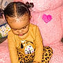 toddler, child, pigtails, yellow_shirt, dog_design, leopard_print_pants, carpet, pink_teddy_bear, stuffed_animal, heart_shape, indoor, cute, sitting, holding, playful, soft_texture, toy, young_child, focused, cozy