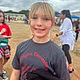 Charlee is registered to the contest to win money with this photo: child, girl, smiling, outdoor, school_event, face_paint, tshirt, blonde_hair, colorful_hair, people, cloudy_sky, grass, casual_clothing, person, portrait, happy, festival, community, daytime, event