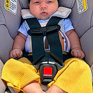 Madeline joined the competition — help win amazing prizes! baby, car_seat, straps, headband, yellow_pants, shirt, infant, child, seatbelt, safety, serious_face, blue_eyes, indoors, cute, hands, feet, warning_labels, clothing, person, portrait