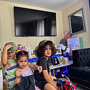 Rose joined the competition — help win amazing prizes! children, indoor, play, toy_motorcycle, cap, curly_hair, black_tshirt, striped_shirt, pigtails, living_room, television, couch, photos, table, curtains, floor, playful, kids, furniture, home