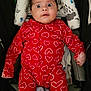 Lucas is registered to the contest to win money with this photo: baby, child, onesie, red_clothing, hearts_pattern, stroller, cushion, headrest, wide_eyes, surprised_expression, infant, seated, indoor, person, cute, adorable, face, portrait, clothing, baby_girl