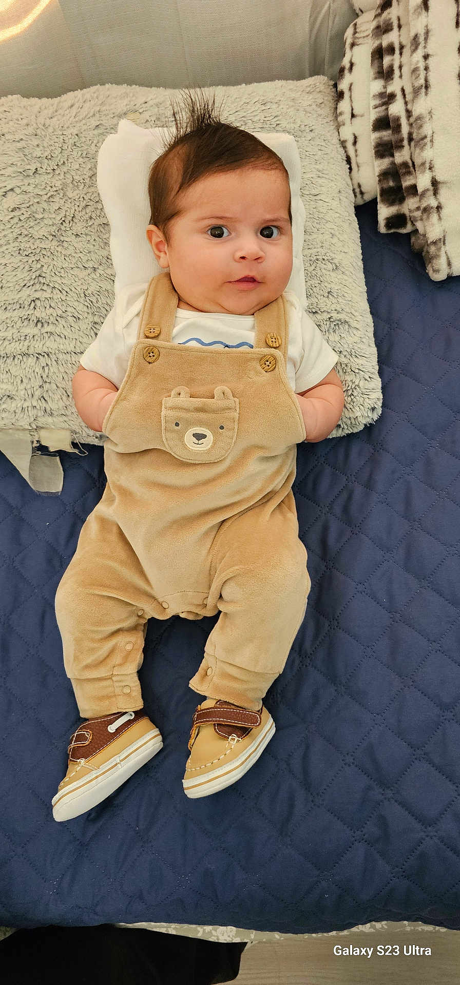 Lucas joined the competition — help win amazing prizes! baby, infant, child, face, eyes, hair, mohawk, clothing, overall, bear, shoes, pillow, blanket, bed, quilt, fabric, cute, lying_down, indoors, portrait