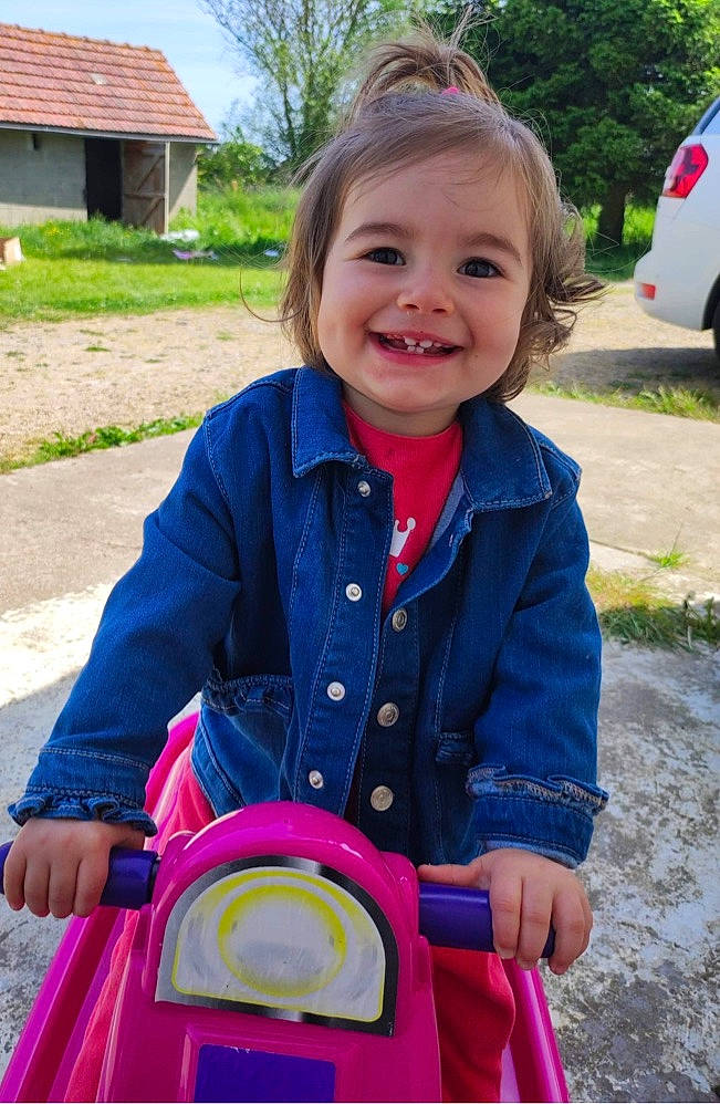 Jade a rejoint le concours — aidez-le/la à gagner de superbes lots ! baby_toddler_clothing, beauty, child, clothing, electric_blue, face, facial_expression, fun, grass, happy, jacket, joy, leisure, motor_vehicle, person, plant, public_space, recreation, riding_toy, smile