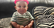 Alexander joined the competition — help win amazing prizes! baby, child, infant, sitting, portrait, indoors, couch, leather, pillow, zebra_pattern, pink_hat, striped_shirt, green_shirt, barefoot, smiling, wide_eyes, living_room, furniture, photography, cute