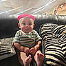 baby, child, infant, sitting, portrait, indoors, couch, leather, pillow, zebra_pattern, pink_hat, striped_shirt, green_shirt, barefoot, smiling, wide_eyes, living_room, furniture, photography, cute