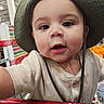 baby, child, infant, face, portrait, smiling, wide_eyes, bucket_hat, hat, shopping_cart, supermarket, store, shopping, clothing, sweater, indoor, closeup, person, retail, happy