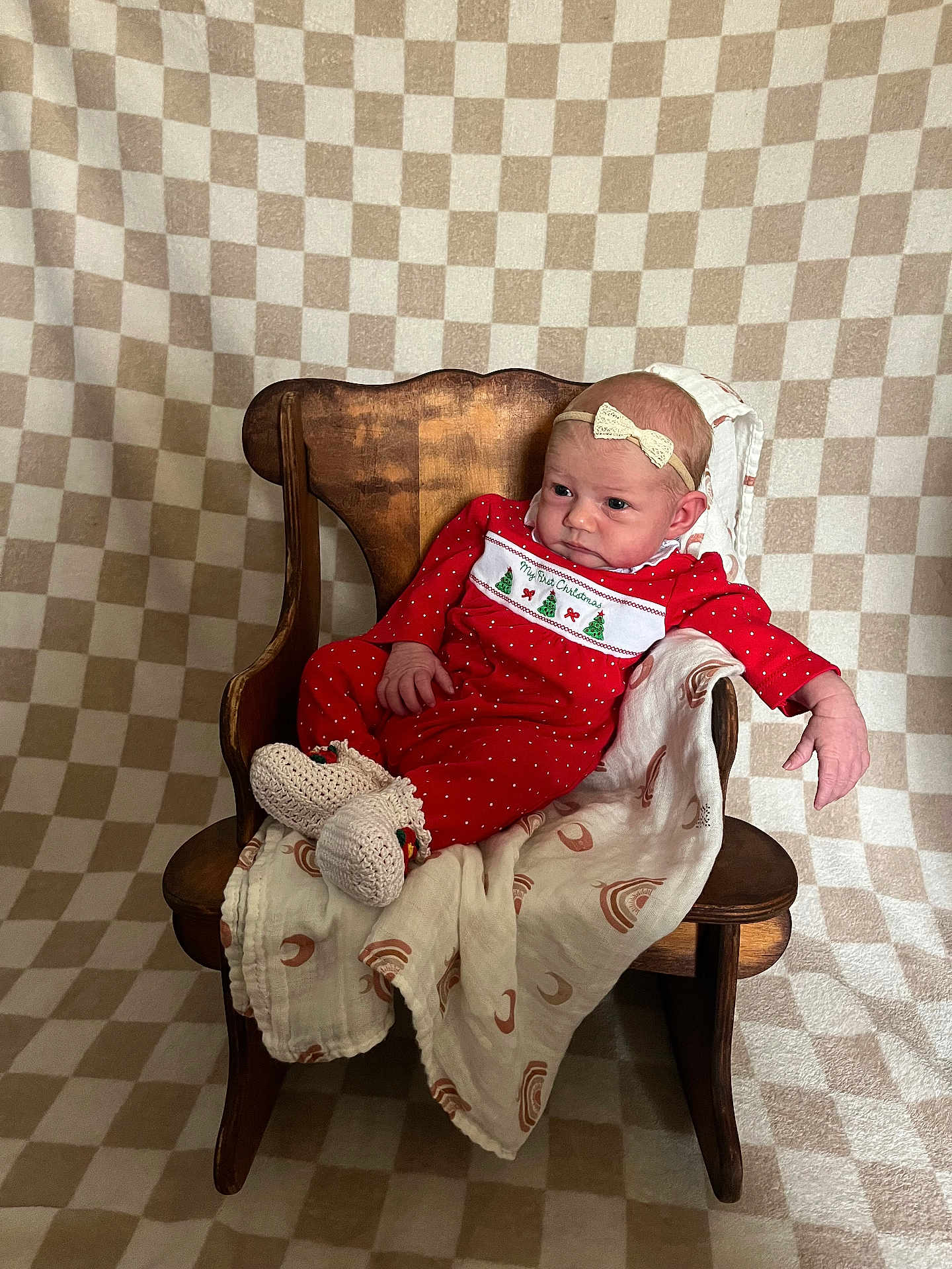 Kristina is registered to the contest to win money with this photo: baby, infant, red_clothing, christmas_theme, wooden_chair, blanket, headband, patterned_background, indoors, portrait, cute, holiday, cozy, smiling, sitting, newborn, warm, decor, soft_lighting, relaxed