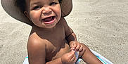 Cyrus joined the competition — help win amazing prizes! toddler, child, beach, sand, hat, smile, sunlight, towel, sitting, happy, footwear, outdoor, summer, cute, playful, barefoot, sunhat, vacation, sandals, portrait