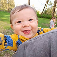 Rocket joined the competition — help win amazing prizes! baby, child, smiling, outdoor, grass, trees, person, blue_eyes, yellow_clothing, happy, face, nature, greenery, playful, blurred_background, casual_clothing, holding_camera, joyful, park, family