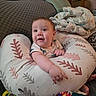 baby, infant, pillow, blanket, couch, indoor, smiling, child, person, furniture, pattern, comfort, reaching, clothing, face, head, arm, foot, home, cozy