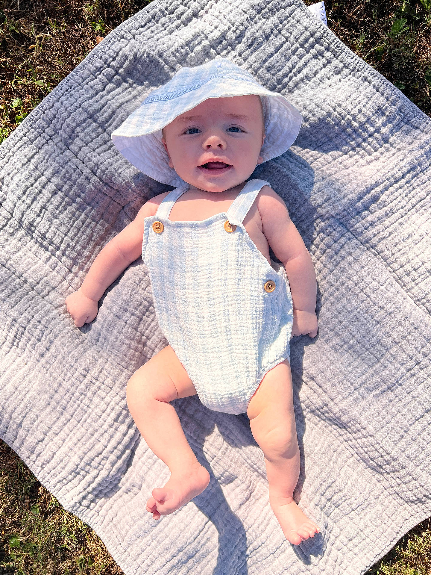 Cohen joined the competition — help win amazing prizes! baby, blanket, bonnet, cap, clothing, dress, face, grass, hat, head, homedecor, pants, person, photography, plant, portrait, quilt, sitting, summer, sunhat