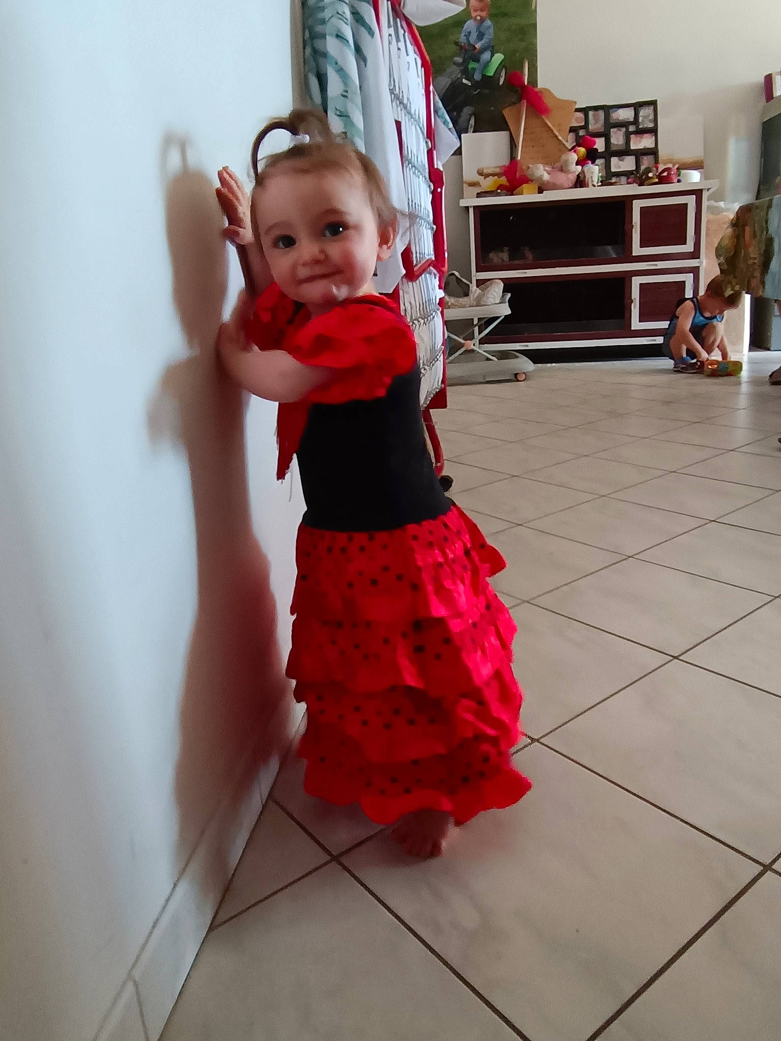 Andréa a rejoint le concours — aidez-le/la à gagner de superbes lots ! baby, baby_toddler_clothing, bookcase, child, dress, event, floor, flooring, happy, magenta, person, pink, red, shelf, sleeve, smile, standing, television, toddler, waist