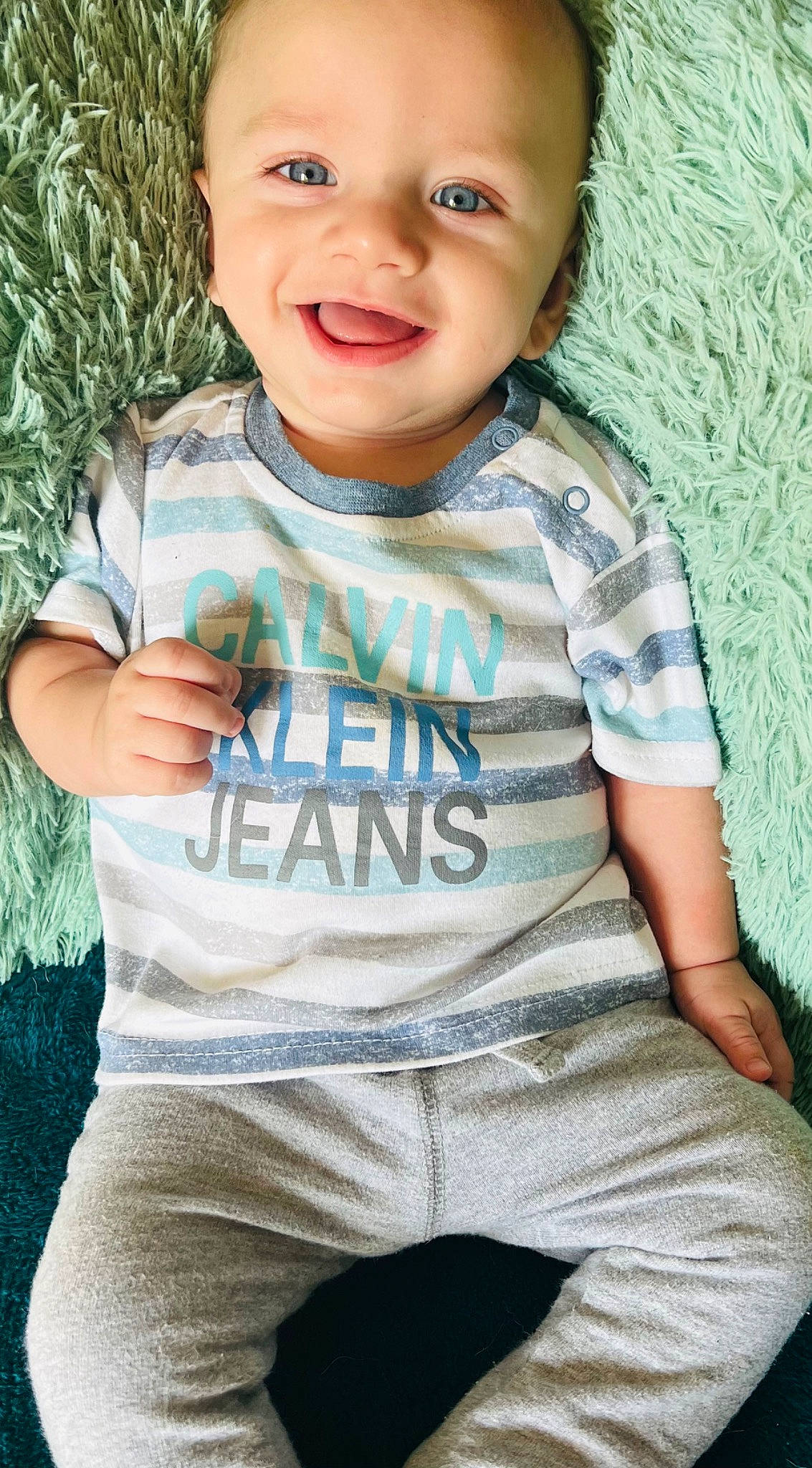 Jaxx is registered to the contest to win money with this photo: baby, baby_toddler_clothing, blue, cheek, chin, cool, gesture, grass, grey, happy, joy, lip, mouth, neck, nose, person, skin, sleeve, smile, standing