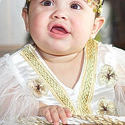 Abby is registered to the contest to win money with this photo: adorable, baby, child, closeup, cute, decorative, embroidery, expression, face, gold_accessory, hand, headpiece, indoor, infant, person, portrait, smile, soft_lighting, white_clothing, wicker_basket