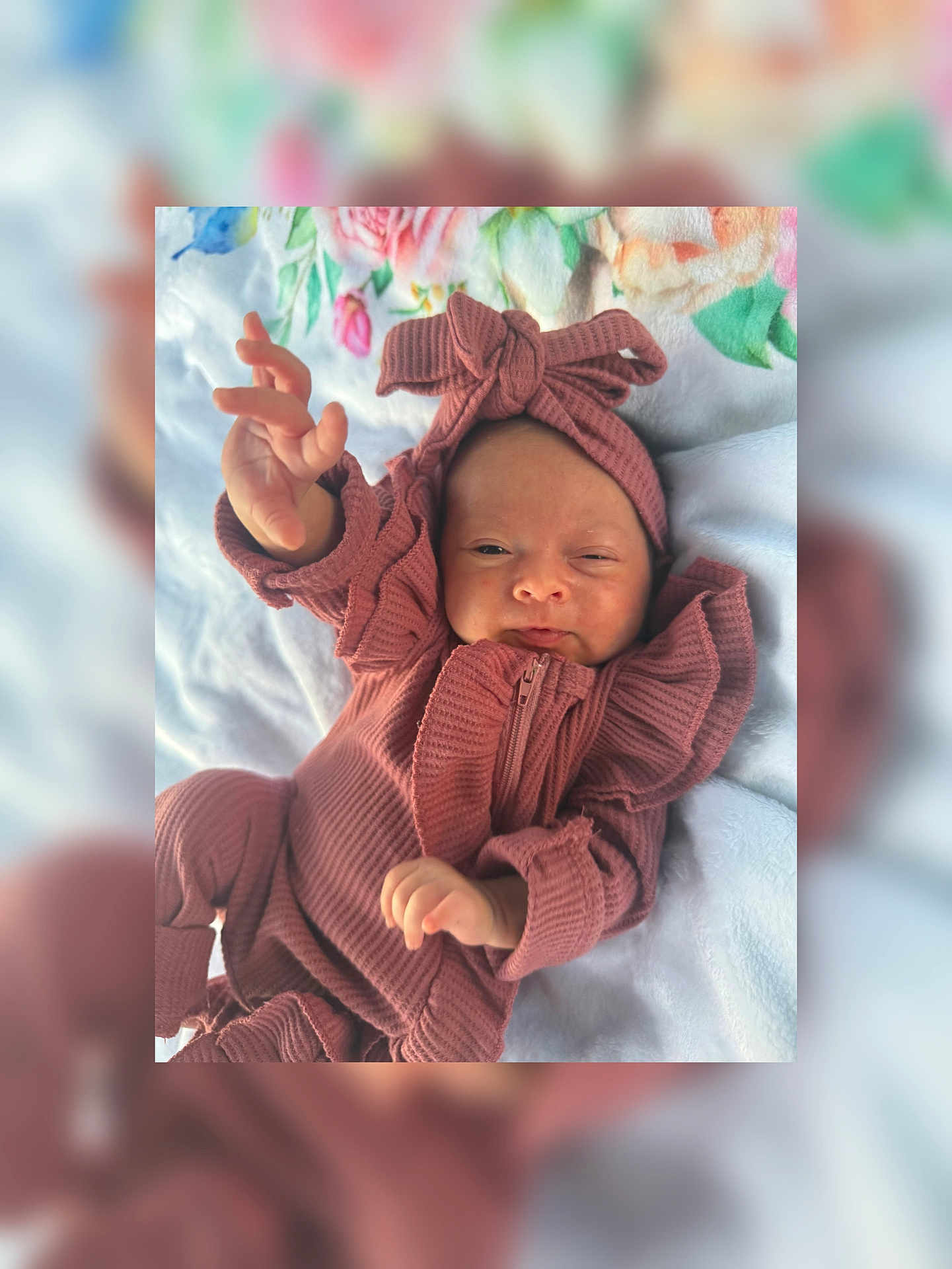 Rynleigh is registered to the contest to win money with this photo: baby, infant, child, blanket, headband, clothing, pink, mauve, hand, face, portrait, lying_down, soft_texture, cute, newborn, expression, cozy, zipped_jumpsuit, ruffles, indoor