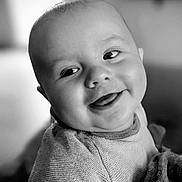 Andréas participe au concours pour gagner de l'argent avec cette photo : baby, smiling, tongue_out, sweater, blanket, face, portrait, close_up, child, cute, infant, happy, soft_light, indoor, cozy, expression, person, young_child, black_and_white, warm