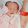 newborn, baby, infant, sleeping, pink_clothing, wrapped, hands, hospital, medical_wristband, allergy_alert, adult_hands, patient, bed, blanket, soft_texture, closeup, portrait, healthcare, resting, peaceful