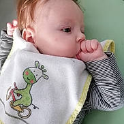 Lyana participe au concours pour gagner de l'argent avec cette photo : baby, infant, thumb_sucking, bib, giraffe_design, striped_clothing, face, head, hand, sleepy, cute, child, lying_down, soft_surface, peaceful, skin, hair, closeup, portrait, indoors