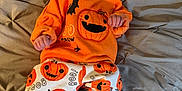 Jesse joined the competition — help win amazing prizes! baby, infant, smiling, orange_clothing, pumpkin_pattern, halloween, blanket, bed, cute, happy, child, person, pajamas, festive, cozy, indoor, soft_fabric, tufted, white_socks, casual