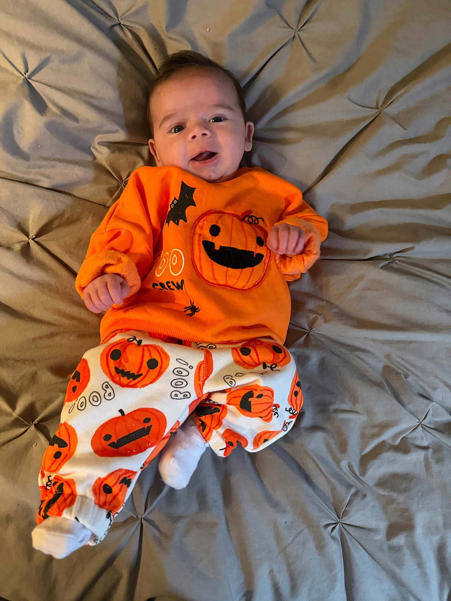 Jesse joined the competition — help win amazing prizes! baby, infant, smiling, orange_clothing, pumpkin_pattern, halloween, blanket, bed, cute, happy, child, person, pajamas, festive, cozy, indoor, soft_fabric, tufted, white_socks, casual