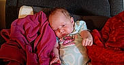 Serenity joined the competition — help win amazing prizes! baby, infant, child, sleepy, sitting, armchair, blanket, red_blanket, pink_blanket, clothing, onesie, portrait, indoor, home, furniture, cozy, relaxed, face, bare_feet, photography