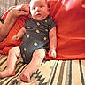 baby, infant, child, portrait, sitting, lying_down, wide_eyed, indoors, red_pillows, blanket, cactus_print, onesie, adult_arm, furniture, couch, textile, cozy, home, patterned_blanket, photography